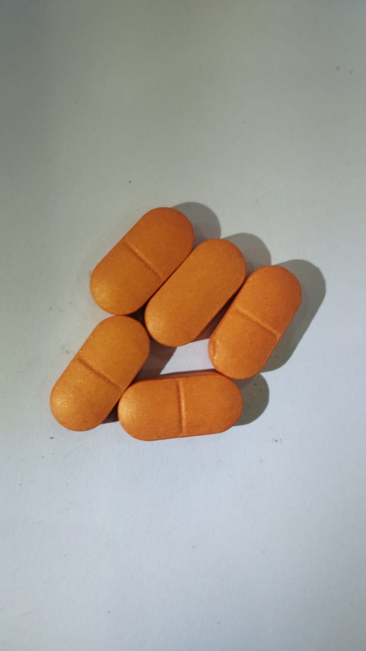 Orange film coated caplets with a break line